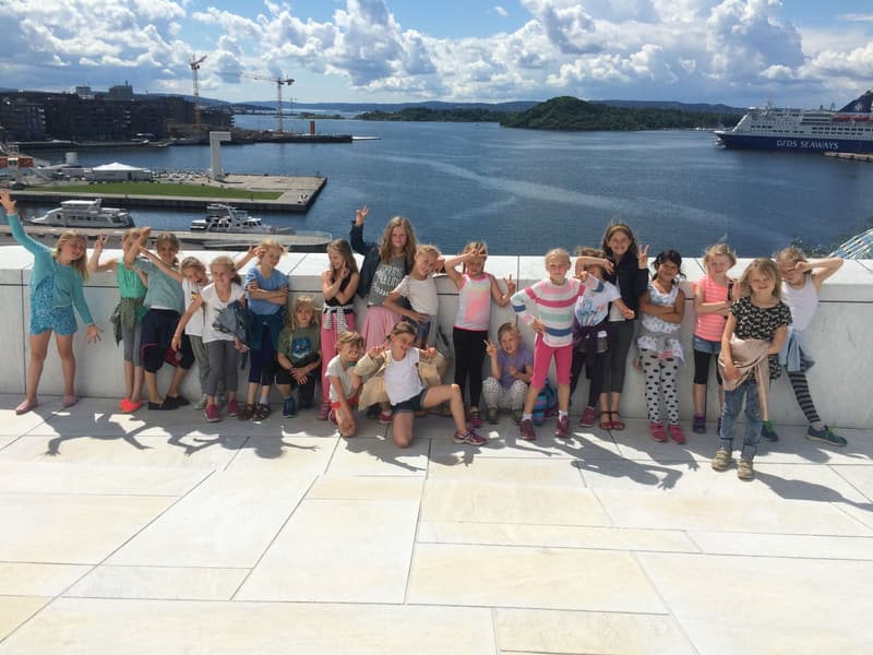 En stor gruppe barn på taket av Operaen med fjorden bak seg