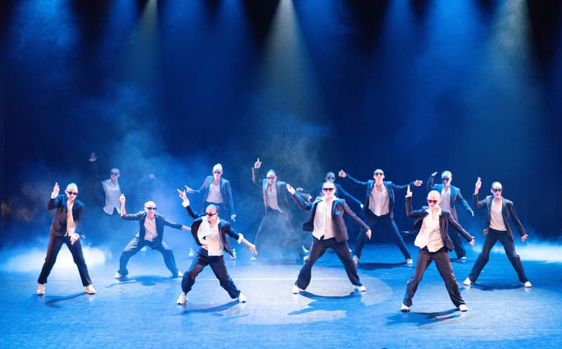 Dansere i dress og solbriller i blått scenelys