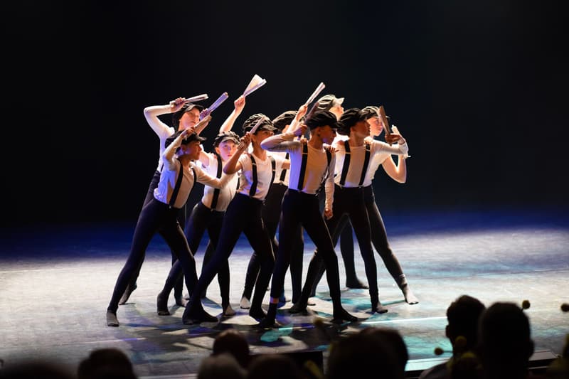 En gruppe dansere med seler og hvite skjorter i en tett formasjon